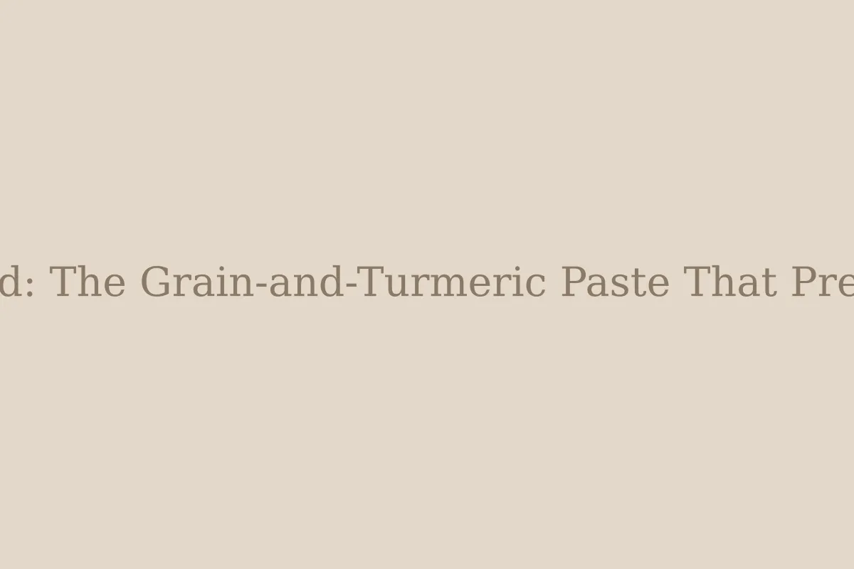 A bowl of golden ubtan powder beside a wooden spoon, raw turmeric and gram flour